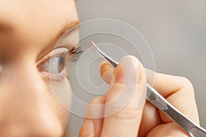 Young Woman Removing Eyebrows Looking At Mirror In Bathroom