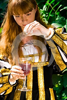 Young woman in renaissance dress poisoning wine