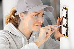 young woman repairs electric socket with screwdriver