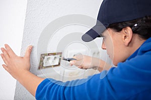 young woman repairs electric socket with screwdriver