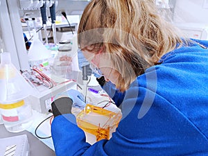 Young woman researcher loading DNA samples to agarose gel