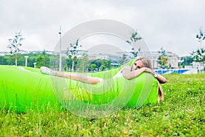 Young woman resting on an air sofa in the park.