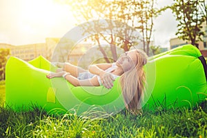 Young woman resting on an air sofa in the park.