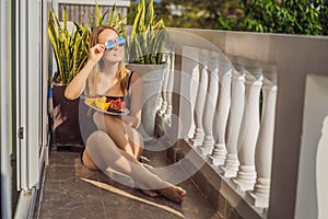 Young woman resting on a balcony with a plate of fruit. life-work balance, relaxation healthy quality living lifestyle