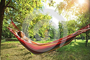 Young woman resting in comfortable hammock at garden