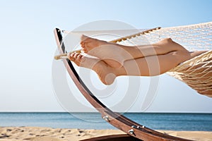 Young woman resting in hammock on beach