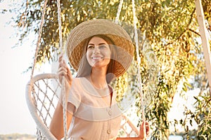 Young woman resting in hammock chair outdoors on sunny day. Summer vacation