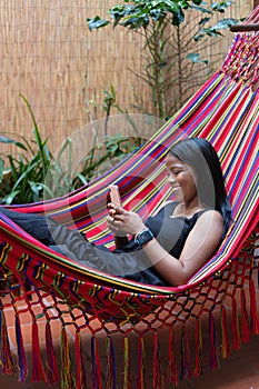 Woman resting in a hammock checking her smartphone photo