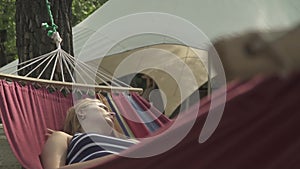 Young woman is resting in a hammock outdoors