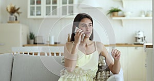 Young woman resting on sofa speak on smartphone