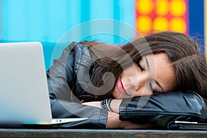 A young woman resting from work lying on folded arms at an outdoor cafe table