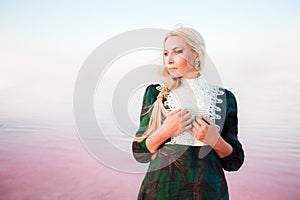 Young woman walking on Dead Sea with beautiful sky at pink sunrise