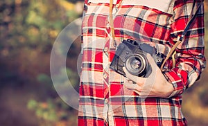 Young Woman with retro photo camera and plaid shirt outdoor
