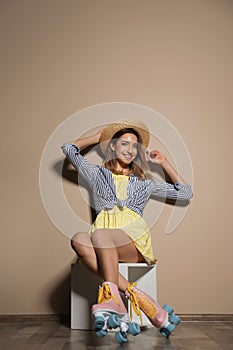 Young woman with retro roller skates against color wall.