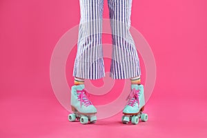 Young woman with retro roller skates on color background