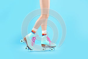 Young woman with retro roller skates on color background