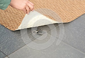 Young woman revealing hidden key under door mat