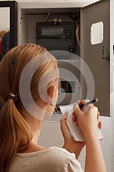 Young woman rewrites the electrical meter readings