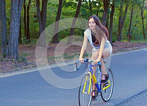 Young woman rides on a bicycle on the road in the park