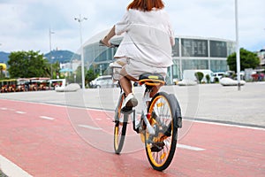Young woman riding bicycle on lane in city, back view