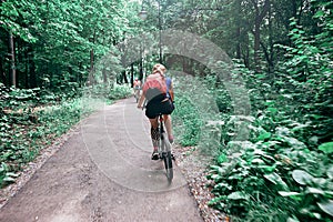 Young woman riding a bicycle in the park in motion, rear view