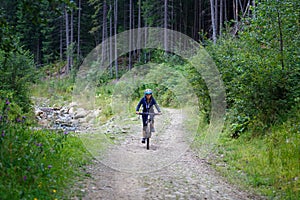 Young woman riding bike on forest trail road