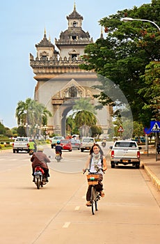 Young woman riding bike near Victory Gate Patuxai