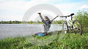 Young woman riding a bike through the park on the background of a lake or river.