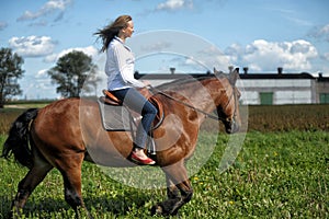 Young woman riding on a brown horse