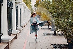 Young woman riding electric scooter in autumn city