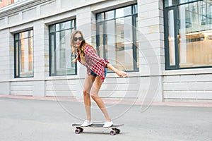 Young woman riding on her skateboard. Female skater practicing skating on the city.