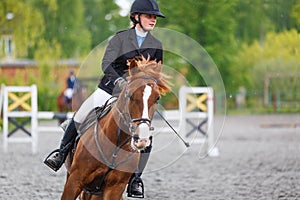 Young woman riding horseback in equestrian showjumping event