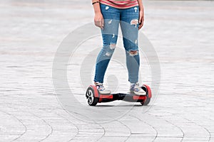 Young woman riding a hoverboard on the city square. New movement and transport technologies. Close up of dual wheel self