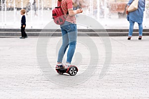 Young woman riding a hoverboard on the city square. New movement and transport technologies. Close up of dual wheel self