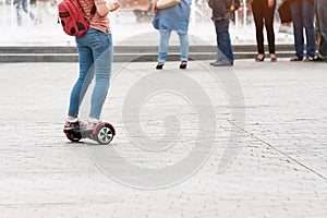 Young woman riding a hoverboard on the city square. New movement and transport technologies. Close up of dual wheel self