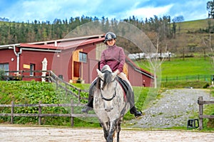 Young woman riding a white horse in a calm equestrian center