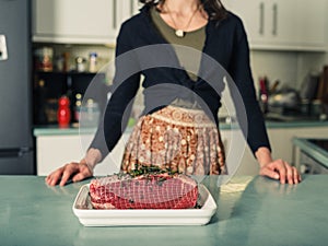 Young woman with roasting joint in kitchen