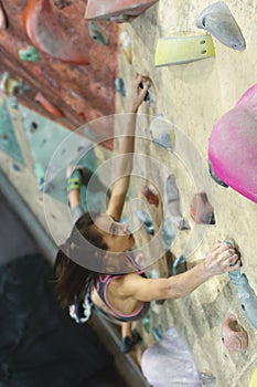 Young Woman Rock climber is Climbing At Inside climbing Gym. slim pretty Woman Exercising At Indoor Climbing Gym Wall