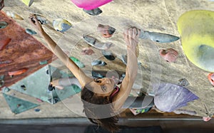 Young Woman Rock climber is Climbing At Inside climbing Gym. slim pretty Woman Exercising At Indoor Climbing Gym Wall