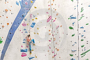Young Woman rock climbing indoors.