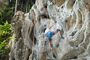 Young woman rock climbing on karst limestone white mountain in Thailand