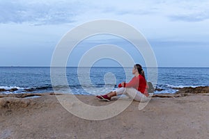 Young woman on Rock seaside. Stoned beach near sea with blue sky