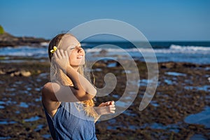 A young woman on a rocky cosmic Bali shore