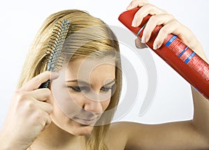 Young woman with roller comb and hairspray