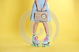 Young woman with roller skates and retro radio on color background