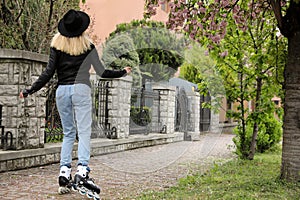 Young woman roller skating on spring day, back view