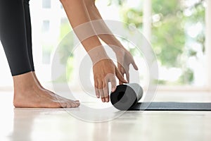 Young woman rolling black yoga mat side view close up photo