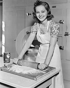 Young woman rolling out dough in the kitchen