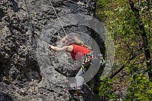 Young woman with a rope engaged in the sports of rock climbing in the rock wall