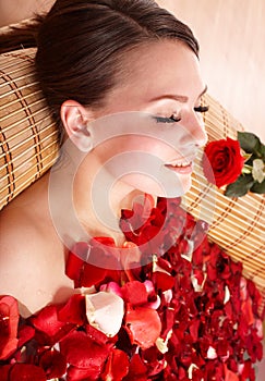 Young woman in rose petal swim water.